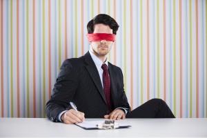 Blindfold businessman at his office signing contracts